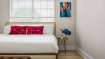 A bedroom with a bed, a nightstand with a lamp, and a painting on the wall.