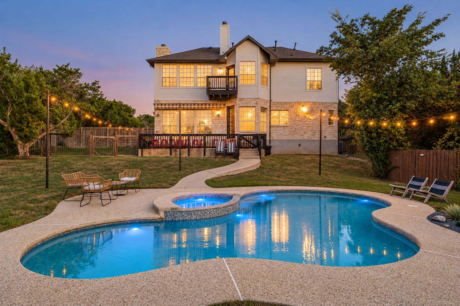 A two-story house with a swimming pool, outdoor seating, and string lights.