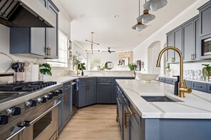 Cocina moderna con una isla central, electrodomésticos de acero inoxidable y muebles azules.