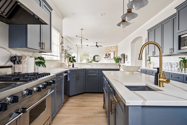 A modern kitchen with a central island, stainless steel appliances, and blue cabinetry.