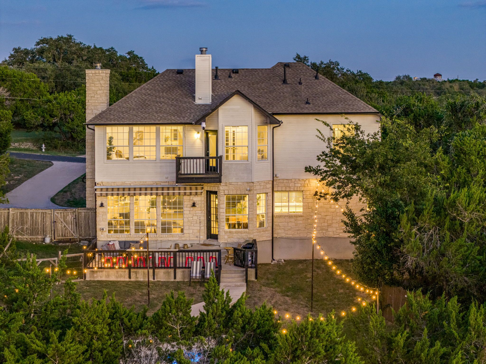 A two-story house with a balcony, a driveway, and a well-lit front porch.