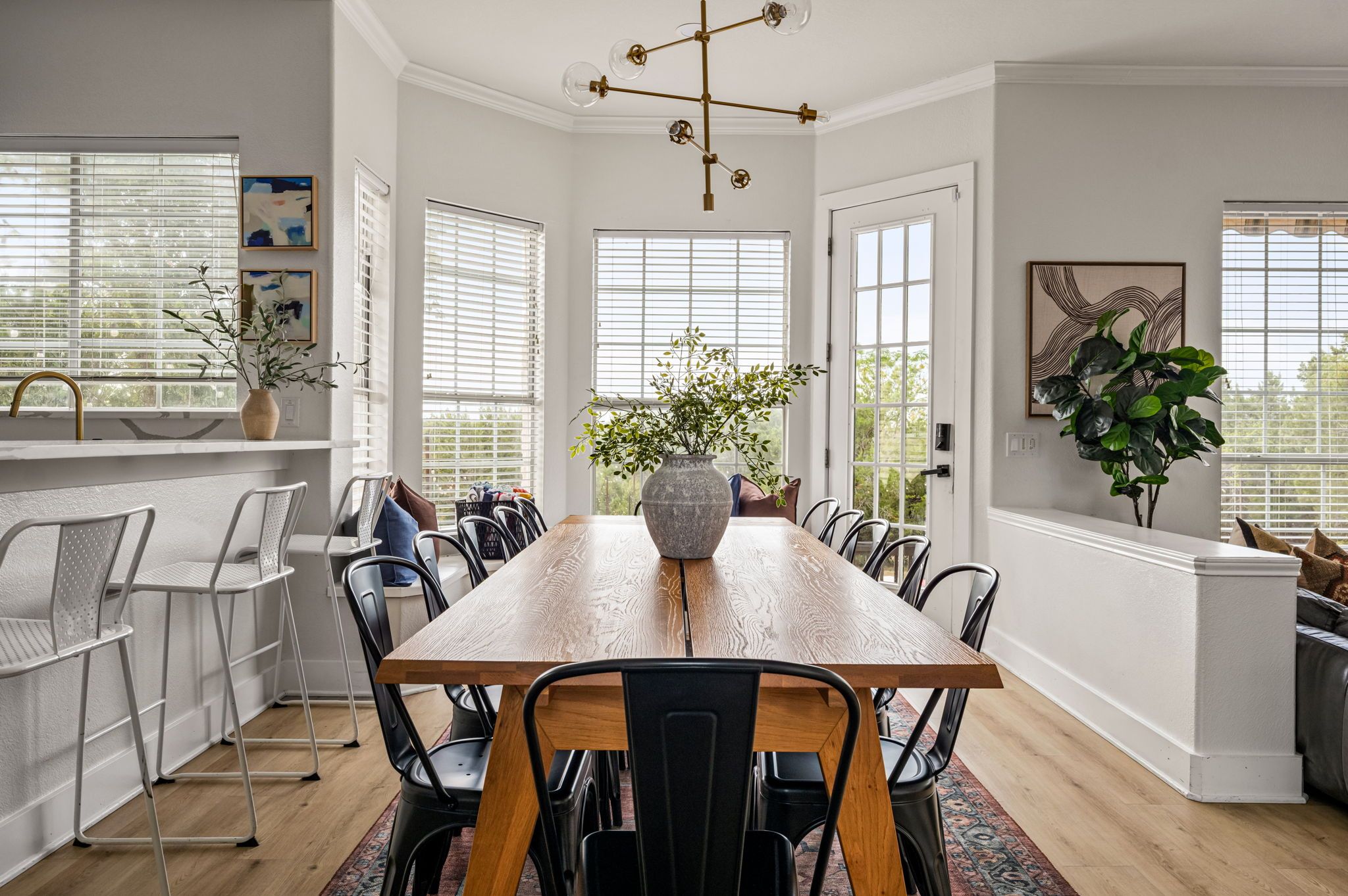 A dining room with a long wooden table, surrounded by chairs, and a vase of flowers in the center.