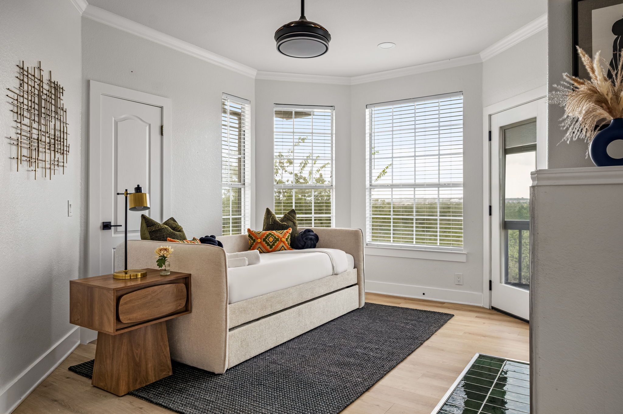 A room with a bed, a bedside table, a lamp, and a window with blinds.