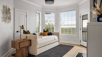 A room with a bed, a bedside table, a lamp, and a window with blinds.