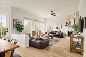 A spacious living room with a fireplace, a dining area with a wooden table, and a seating area with a sofa and chairs.