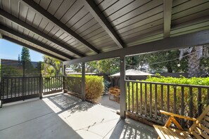 A covered outdoor area with a wooden ceiling, a metal gate, and a seating area with a table and chairs. - Charming Atwater Village Retreat 2BR + 2BA (Los Angeles)