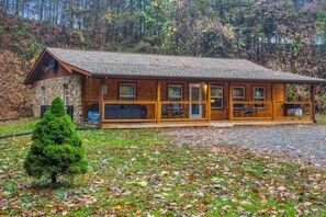Un chalet doté d’une façade en pierre, d’un revêtement extérieur en bois et d’un porche couvert avec des sièges.