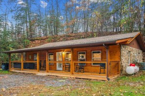 Eine Holzhütte mit großen Fenstern und einer Veranda mit Sitzgelegenheiten.