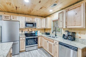 Eine moderne Küche mit Holzschränken, Edelstahlgeräten, Granit Arbeitsplatten und einer eingebauten Mikrowelle.