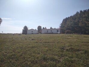 A white single-story house with a front porch and a large yard.