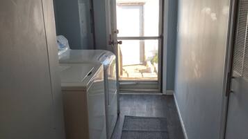 A laundry area with a washing machine, a dryer, and a door leading to a balcony.