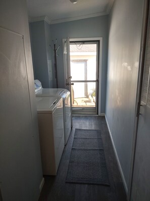A laundry area with a washing machine, a dryer, and a door leading to a balcony.