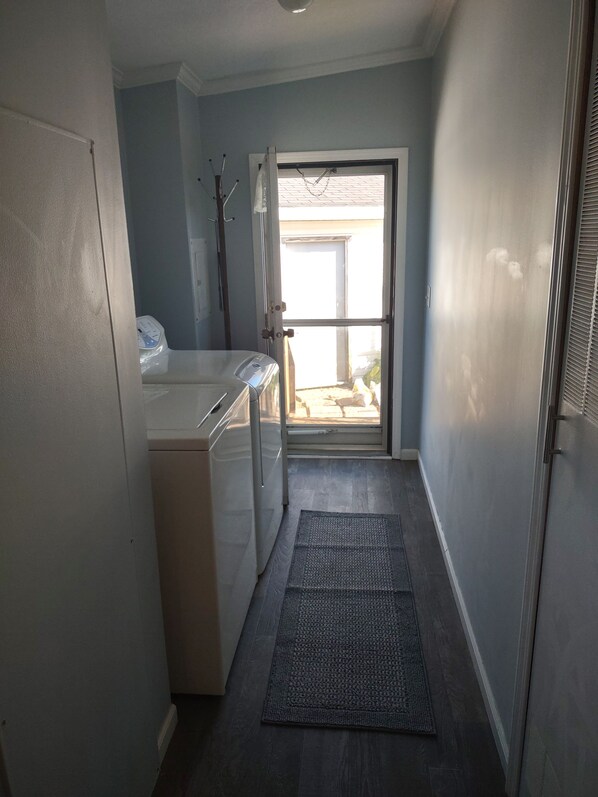 A laundry area with a washing machine, a dryer, and a door leading to a balcony.
