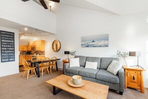 A modern living room with a sofa, coffee table, and dining area. - Steps to Gondola | Upper Village Loft | BBQ Deck | Fitness Room (Whistler)