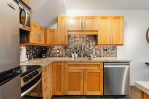 A kitchen with wooden cabinets, a granite countertop, a Bosch dishwasher, and a stove. - Steps to Gondola | Upper Village Loft | BBQ Deck | Fitness Room (Whistler)