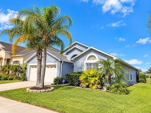 A residential house with a garage, a well-maintained lawn, and a palm tree. - Perfect pool house with waterfront for the best Disney experience in Kissimmee. (Kissimmee)