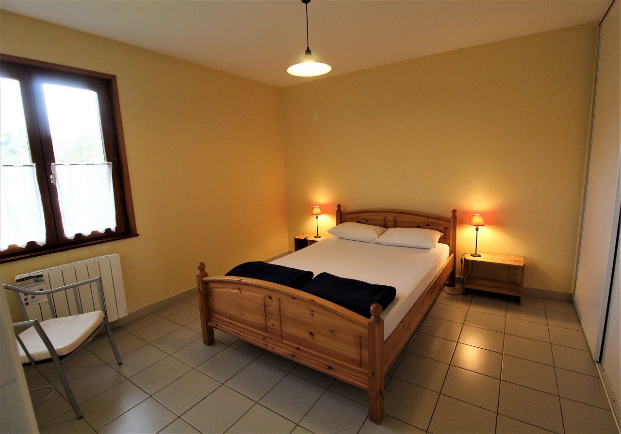 Een slaapkamer met een houten bed, twee bedlampen, een stoel en een radiator.