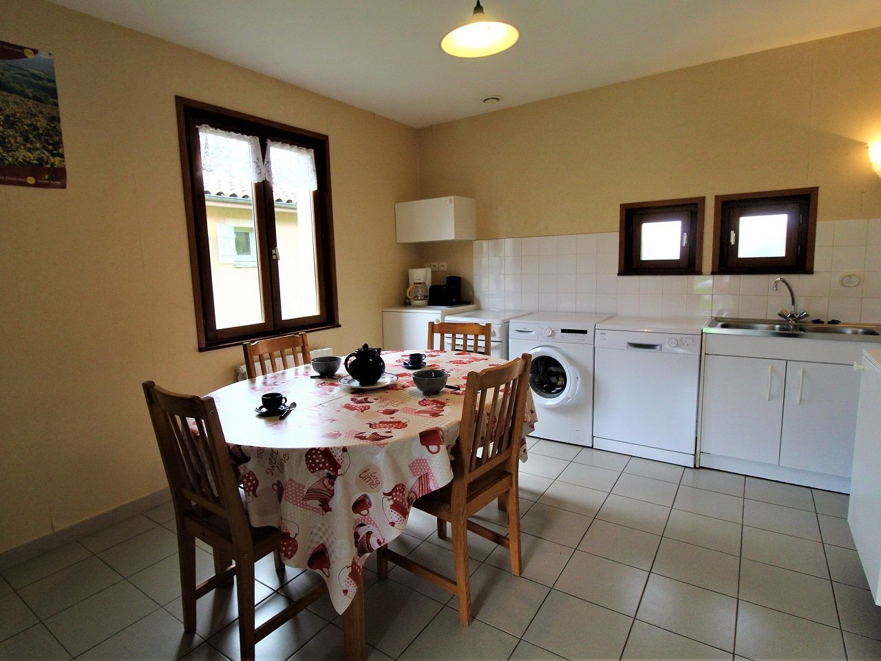 Una cocina con mesa, sillas, lavadora y lavaplatos.