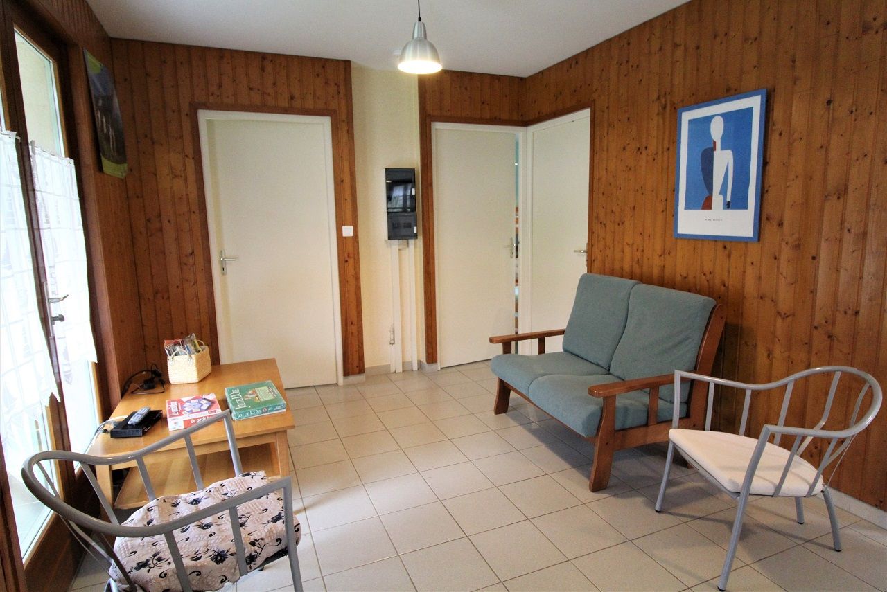 Une pièce avec un mur en bois, une table à manger avec des chaises, un canapé et un téléviseur.