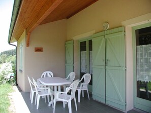 Un patio al aire libre con una mesa y sillas, un letrero que dice 'Lotus' y contraventanas verdes en las ventanas.
