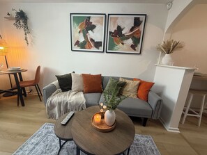 A living room with a grey sofa, a round coffee table with a candle, and two abstract paintings on the wall. - Cosy & Modern 2 bed house |Close to City Centre| Driveway (Nottingham)