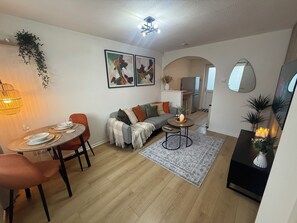 A modern living room with a dining area, a sofa, a coffee table, and a kitchen in the background. - Cosy & Modern 2 bed house |Close to City Centre| Driveway (Nottingham)