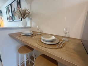 A dining table set with plates, cutlery, and two wine glasses, with a vase of dried plants on the window sill. - Cosy & Modern 2 bed house |Close to City Centre| Driveway (Nottingham)