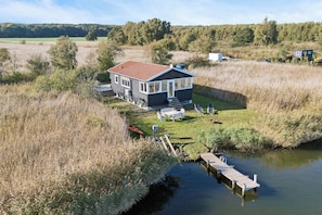 A house with a red roof, a dock, and a grassy yard. - Cozy holiday home with private jetty (Randers NØ)