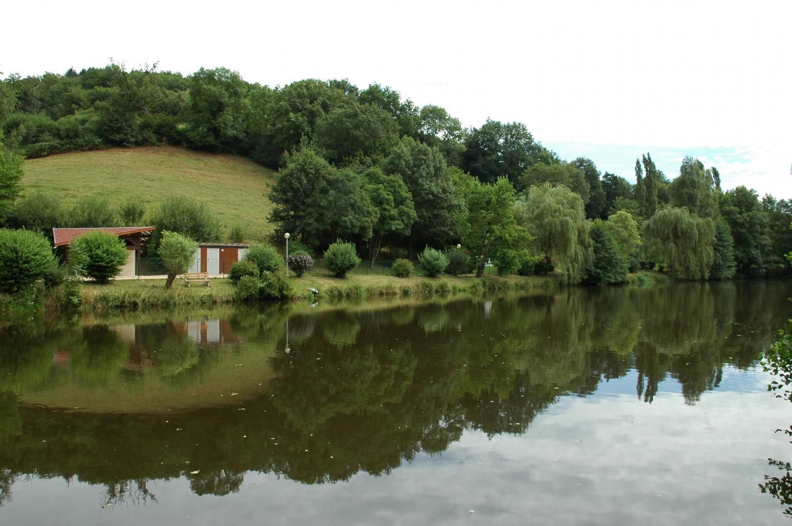 Un’atmosfera tranquilla sulle rive di un lago, con un piccolo edificio immerso nel verde e alberi.