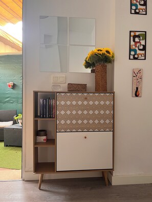 Ein Zimmer mit Bücherregal, einer dekorativen Vase mit Sonnenblumen und einem Wandspiegel.