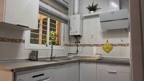 Eine moderne Küche mit weißen Schränken, einem Fenster mit Aussicht, einem eingebauten Herd und einer Arbeitsplatte mit Wasserkocher.