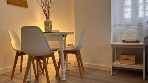 A dining area with a white table and chairs, a vase with branches, and a lamp on a side table. - Nao Haus & Metro Seville (San Juan de Aznalfarache)