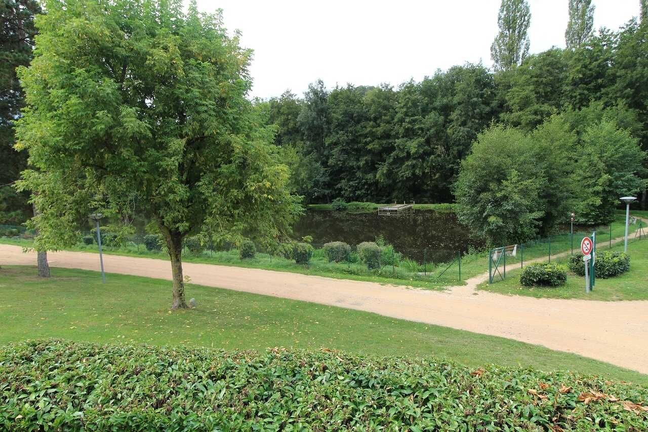 Een park met een onverhard pad, een vijver en een verboden toegangsbord.