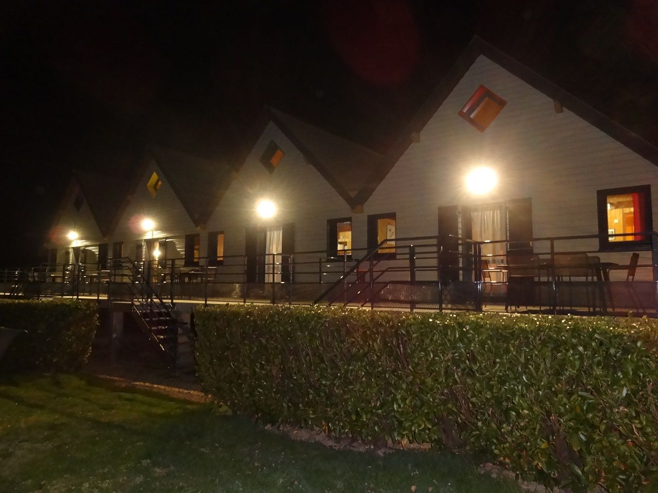 Een rij gebouwen met open wenteltrappen en ramen, verlicht door kunstlicht.