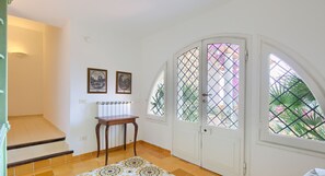 A room with a staircase, a table, two framed pictures, and a door with a window. - Apartment with Sea View a few steps from the beach (Massa Lubrense)