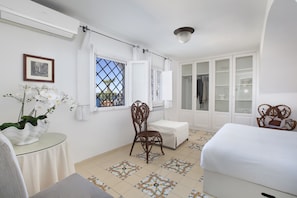 A bedroom with a bed, a chair, a small table, a window with curtains, and a wardrobe. - apartment a few meters from the beach (Massa Lubrense)