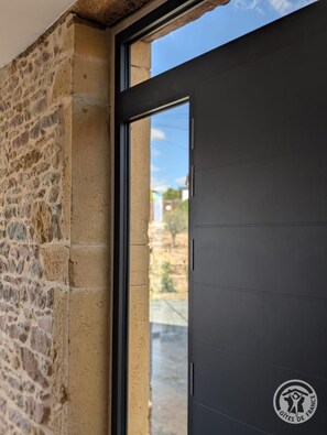 A stone wall adjacent to a modern door with a window.