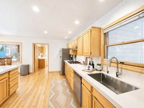 A modern kitchen with wooden cabinets, a stainless steel sink, and a large window. - Family Basecamp - Close to Lake Tahoe, Beaches, Trails & Ski Resorts (Tahoe City)