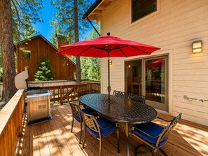 An outdoor deck with a metal table and chairs, a red umbrella, and a grill. - Family Basecamp - Close to Lake Tahoe, Beaches, Trails & Ski Resorts (Tahoe City)