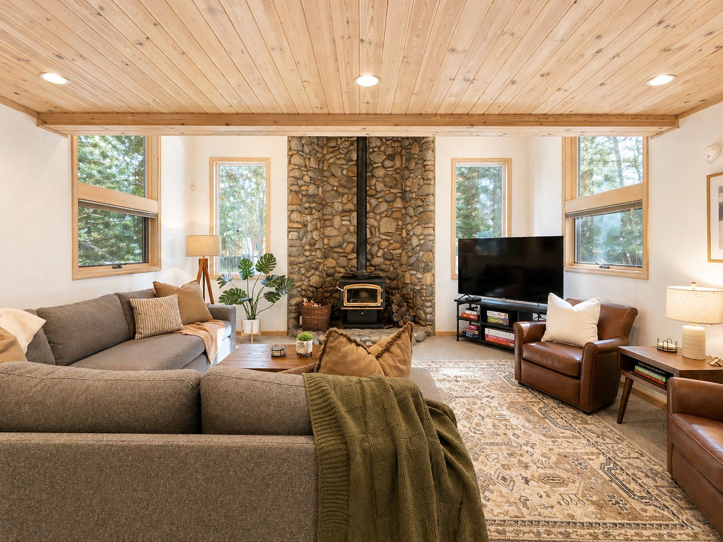 A cozy living room with a stone fireplace, a television, and comfortable seating.