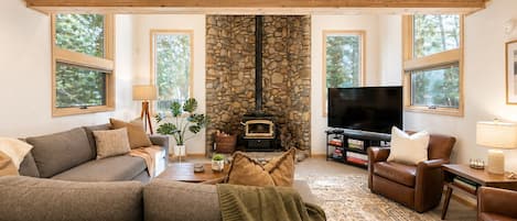 A cozy living room with a stone fireplace, a television, and comfortable seating.