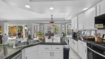 A modern kitchen with white cabinets, a black countertop, and a central island.
