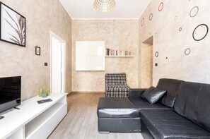 A modern living room with a black leather sofa, a white entertainment unit, and a bookshelf. - Riari 59, Rome - Trastevere (Roma)