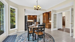 A spacious dining area with a round table, chairs, and a chandelier. - The Eagle's Nest by Avantstay 6-acre Oak Harbor Retreat Fire Pit Mt. Baker + Ocean Views (Oak Harbor)