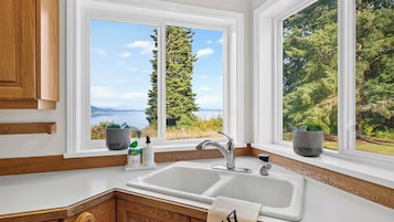 A kitchen with a large window, a sink, and wooden cabinetry.