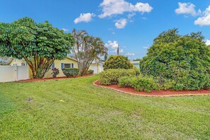 A residential property with a well-maintained lawn, a variety of shrubs, and a clear blue sky. - Heated Pool, Luxury Furnishings, Equipped Kitchen, Close to Beach and Downtown (Stuart)