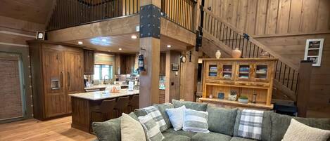 A spacious living area with a green sectional sofa, a wooden coffee table, and a staircase leading to an upper level.