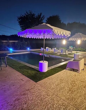 A swimming pool area with a covered seating area and lounge chairs. - Event Space with secluded pool and yard near Hobby Airport (Houston)