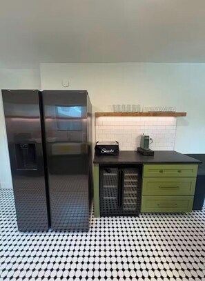A kitchen with a refrigerator, a coffee maker, and a snack bag on the counter. - Event Space with secluded pool and yard near Hobby Airport (Houston)