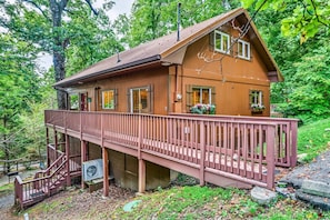 A two-story wooden cabin with a balcony, surrounded by trees. - Halfway to Heaven · Hot Tub, Game Room, Mtn View (Gatlinburg)
